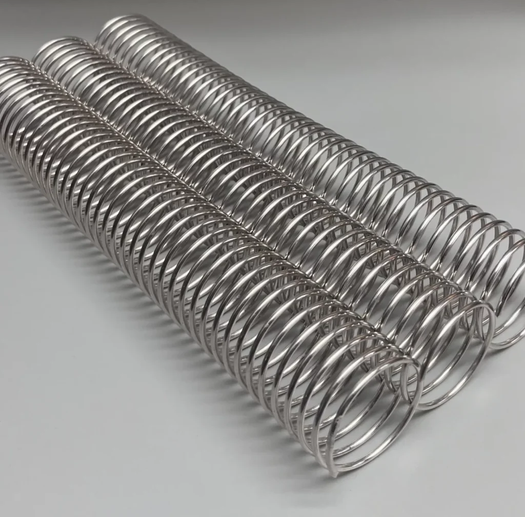 A single 1+3/8" x10" #4 aluminum piece is parallel to three metal springs on a plain gray surface.