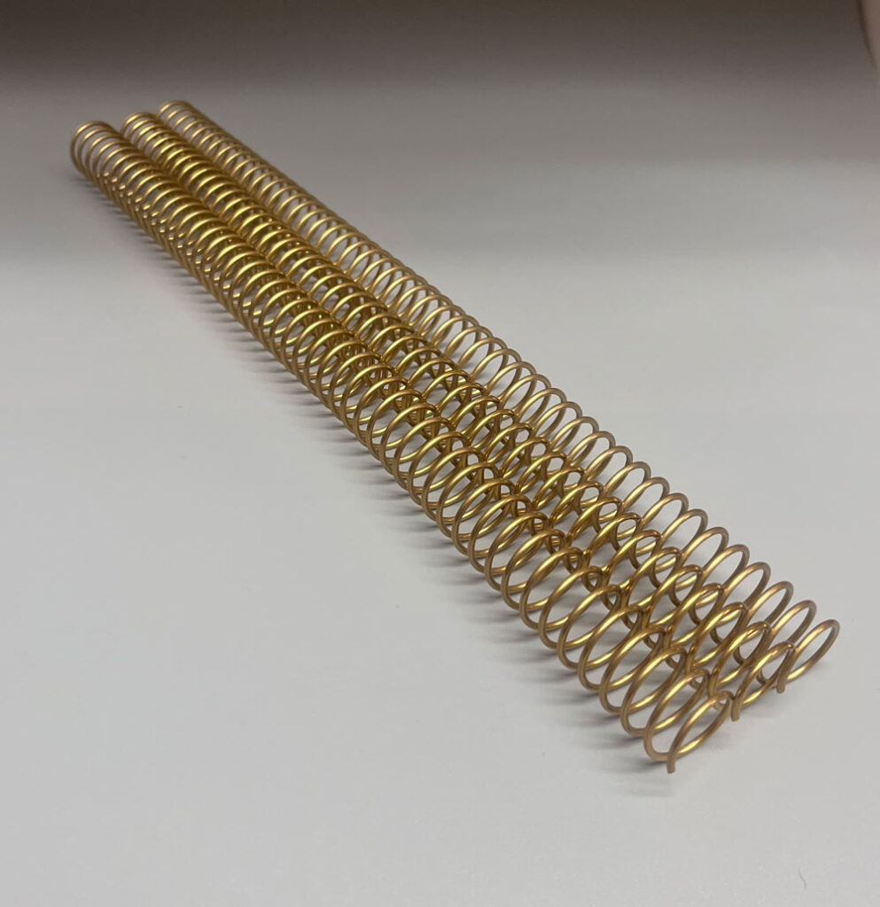 A single 5/8" x 12" #4 gold solid spiral on a white surface.